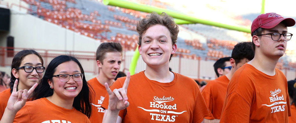 Students showing the "hook em" hand sign